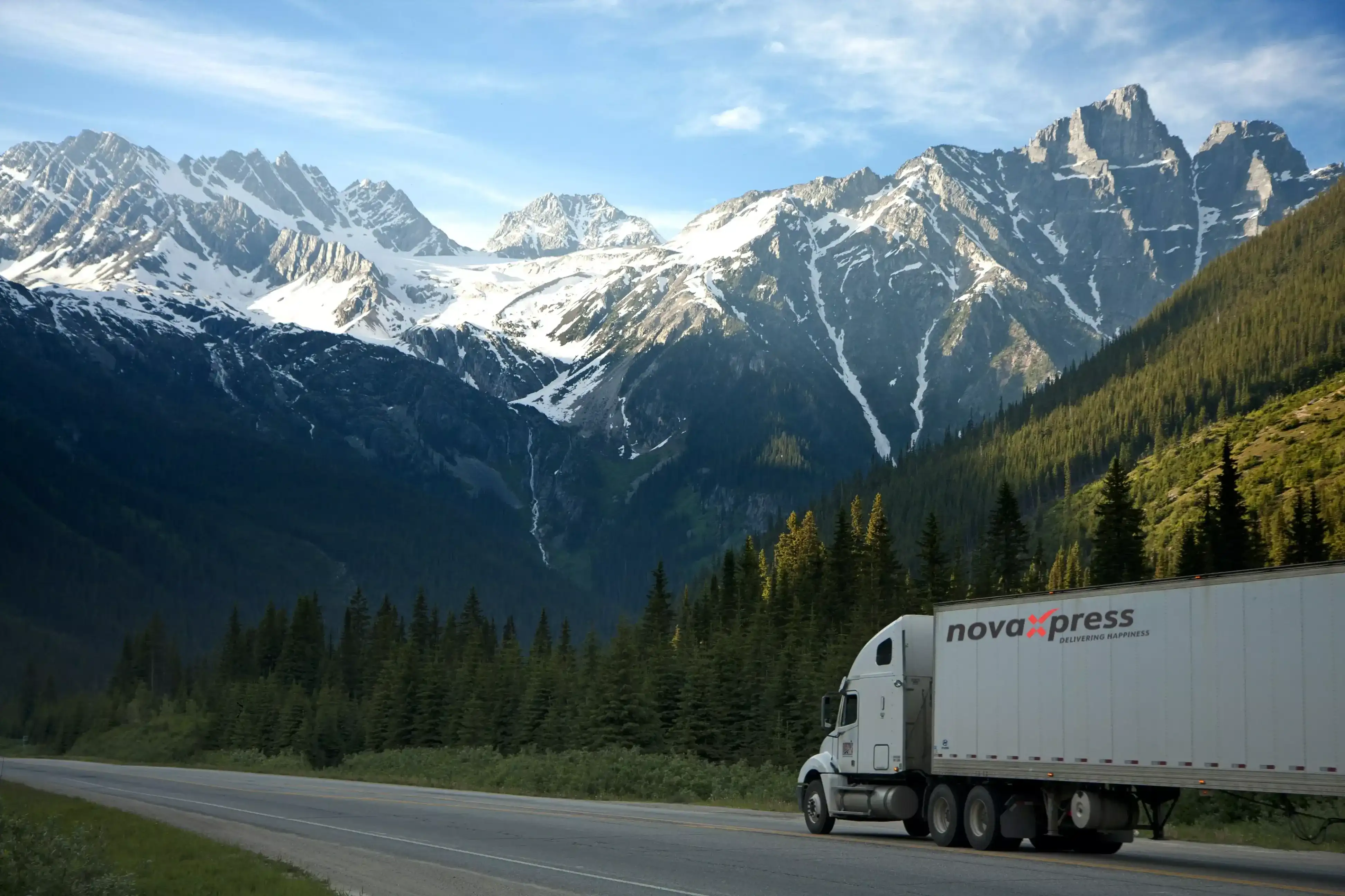 A semi truck driving on a road with mountains in the background.